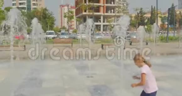 年轻女孩在城市公园喷泉里玩得开心视频的预览图