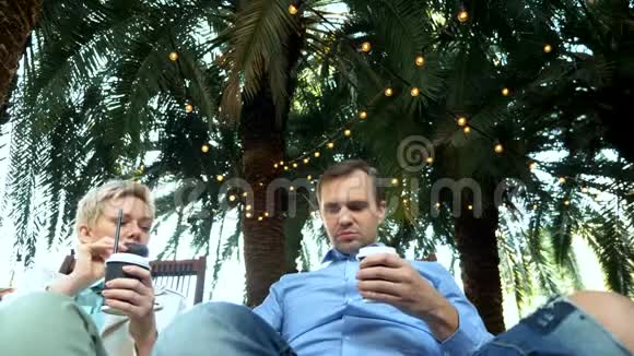 美丽的一对男女在棕榈树下的户外咖啡馆喝咖啡视频的预览图