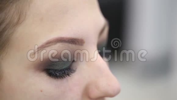 化妆师用化妆刷画一个年轻女孩的眼睑视频的预览图
