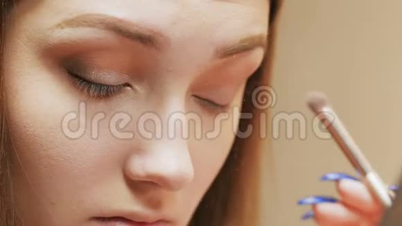 自信的年轻女子用刷子照着小镜子把眼影涂在眼睑上漂亮的女孩化妆了视频的预览图
