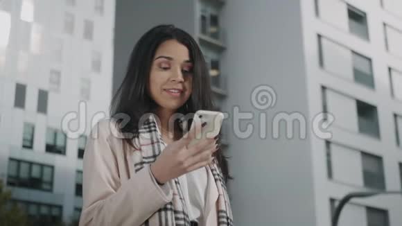 笑的商业女性在智能手机户外阅读信息的肖像视频的预览图