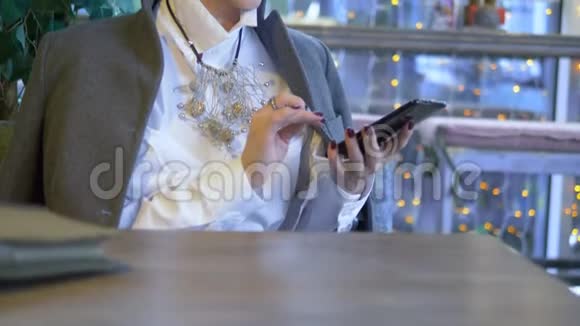 优雅时尚的金发女人坐在咖啡馆里用手机视频的预览图