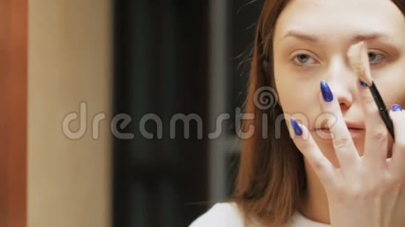 自信的年轻女人用化妆刷做荧光笔漂亮的女孩把化妆品放在脸上照镜子视频的预览图