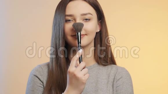 有趣的女孩在一个粉彩的背景擦鼻子和刷子女人化妆概念女性漂亮化妆品一个视频的预览图