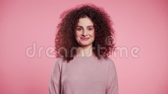 年轻的卷发女人时髦的闪光雀斑化妆粉红工作室背景上调情美丽女孩的肖像视频的预览图
