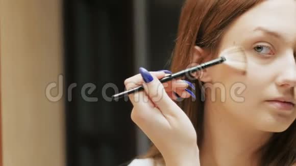 自信的年轻女人用化妆刷做荧光笔漂亮的女孩把化妆品放在脸上照镜子视频的预览图