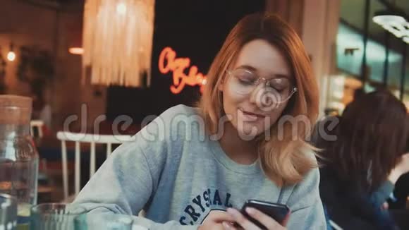 在咖啡馆里用电话和喝咖啡的年轻女人的肖像视频的预览图