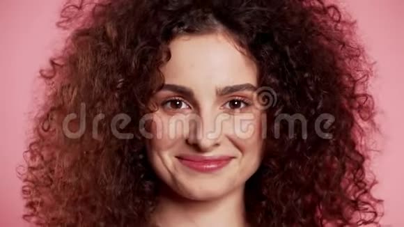 年轻的卷发女人时髦的闪光雀斑化妆粉红工作室背景上调情美丽女孩的肖像视频的预览图