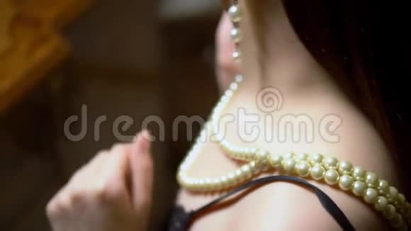 美丽的女孩戴着项链坐在镜子前的黄昏视频的预览图