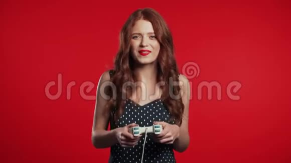 漂亮的年轻女孩在TV上玩电子游戏红色工作室墙上有操纵杆利用现代技术视频的预览图