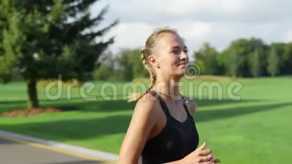 微笑的女运动员在绿色公园慢跑女人晨练视频的预览图
