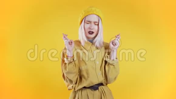 可爱的年轻女孩有五颜六色的发型在黄色的背景下祈祷女人求人4k视频的预览图