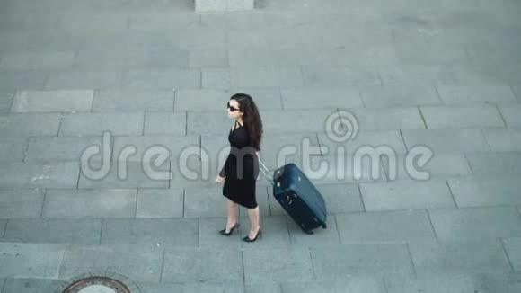 侧视女人带着手提箱走路穿着裙子看着街边的女人视频的预览图