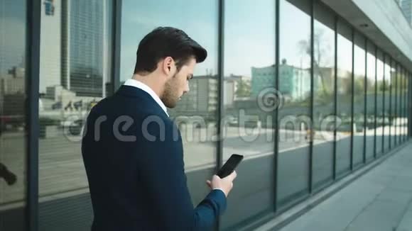 后景商人带着电话走在户外使用智能手机的人视频的预览图