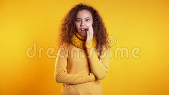 积极的女孩用手指在她的嘴唇上的黄色背景什赫的姿态视频的预览图