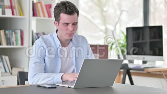 头痛的年轻人在笔记本电脑上工作视频的预览图