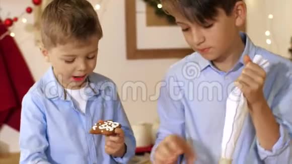 两个兄弟正在家里的厨房里用糕点包装饰一个圣诞饼干视频的预览图