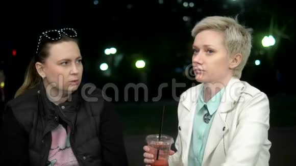 两个女人晚上在街上聊天喝着鸡尾酒视频的预览图