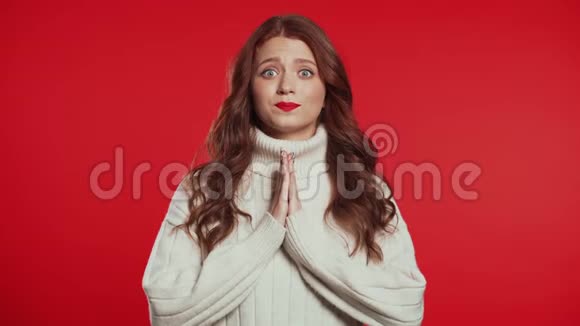 可爱的年轻女孩美丽的发型祈祷红色背景女人求人4k视频的预览图