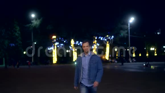 一个穿夹克衫的帅哥晚上在一条城市街上看着摄像机视频的预览图