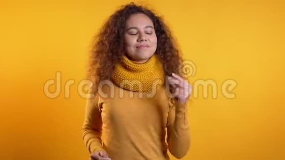 一位留着卷发的美女双手在黄色工作室跳舞视频的预览图