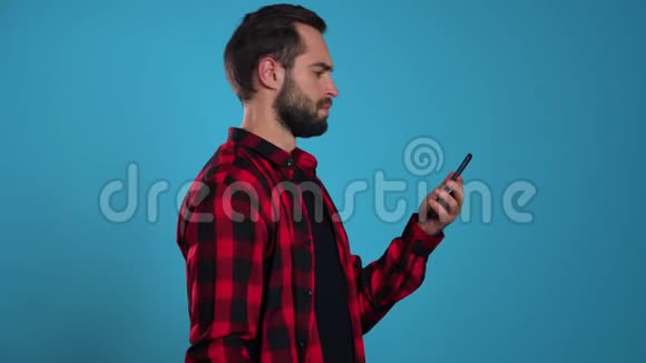 愤怒的现代时髦女郎穿着红色格子衬衫尖叫着放下手机穿着忧郁的蓝色背景男人视频的预览图