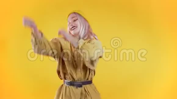 在色彩斑斓的黄色工作室背景下美丽的女人带着时髦的头发跳舞视频的预览图