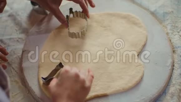 在厨房桌上用饼干刀切面团的特写女人和女孩视频的预览图