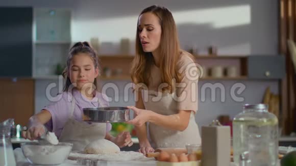 在厨房教女儿筛面团的女人视频的预览图