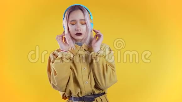 带着黄色背景的耳机跳舞的粉色头发美女视频的预览图