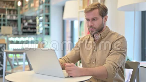 在咖啡厅使用笔记本电脑的进攻性年轻人视频的预览图