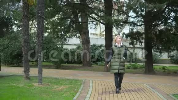 秋天美丽时尚的金发女郎在城市公园散步视频的预览图