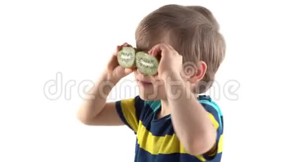 小男孩在画室里摆着白色背景用切奇异果代替眼睛视频的预览图