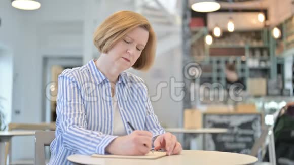 体贴有创意的老女人在咖啡厅做文书工作视频的预览图