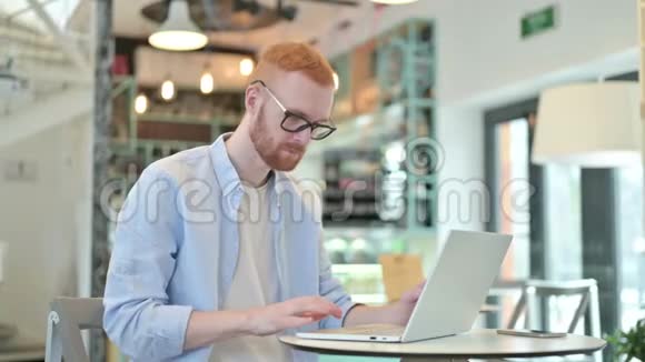 红发男子在咖啡厅进行电脑聊天视频的预览图