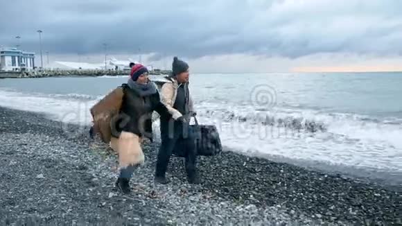 快乐的无家可归夫妇一男一女在海滩上奔跑视频的预览图