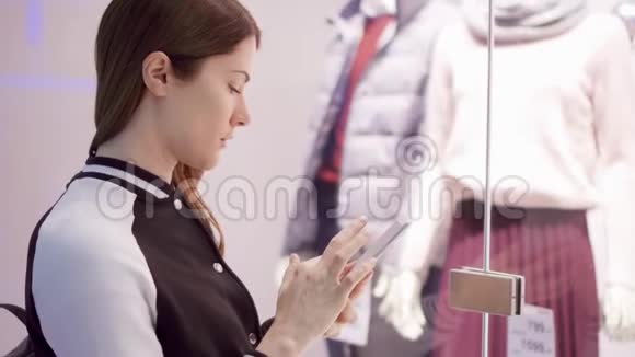 一个年轻的女人在橱窗店附近和男人通过智能手机阅读二维码在线查看价格视频的预览图