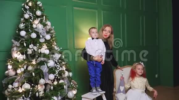 母亲和两个孩子在家中的圣诞树附近视频的预览图