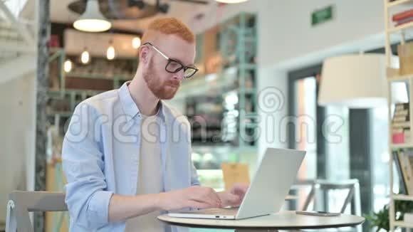 职业红发男子在咖啡厅使用笔记本电脑视频的预览图