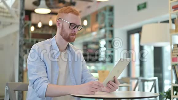 红发男子在咖啡厅桌上进行视频聊天视频的预览图