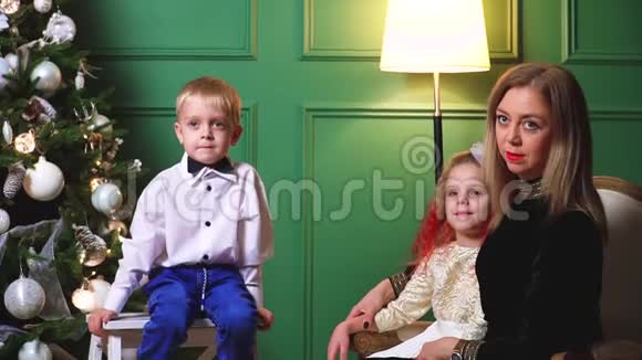母亲和两个孩子在家中的圣诞树附近视频的预览图