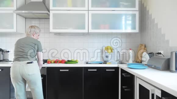 一个女人在家里的厨房里洗蔬菜和水果视频的预览图