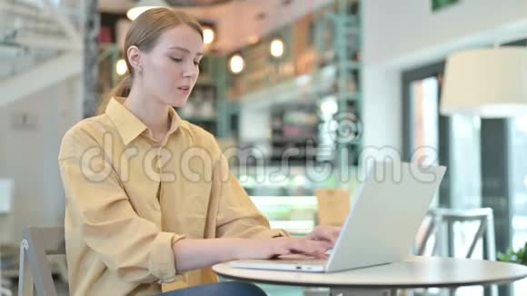 有头痛的年轻女子在咖啡厅使用笔记本电脑视频的预览图
