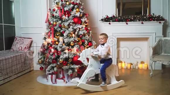 一个美丽的小男孩在一棵装饰着的圣诞树的背景上挂着灯视频的预览图