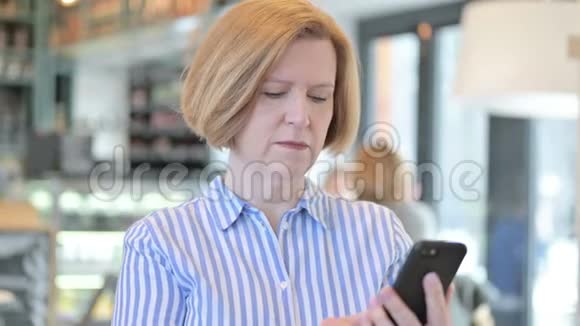 愤怒的创意老女人在智能手机上说话的画像视频的预览图