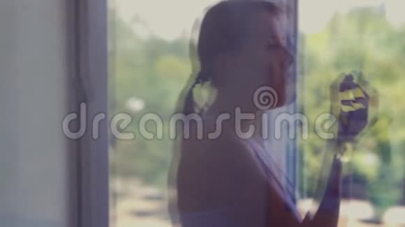 在窗外的倒影中女孩在阳台上吃蛋糕在家里公园视频的预览图