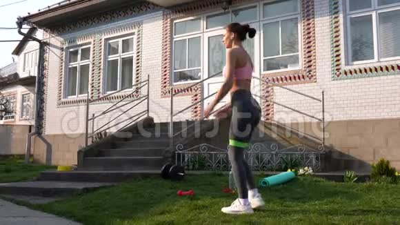 强壮的女人在运动中使用阻力带年轻女子在家户外健身视频的预览图