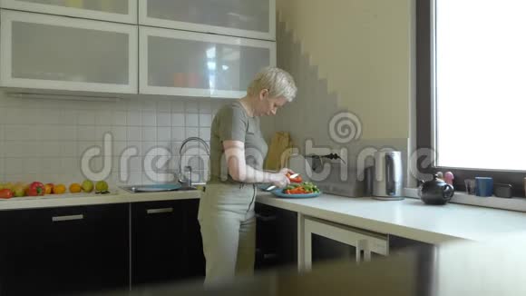 女人在家里的厨房里切蔬菜做零食视频的预览图