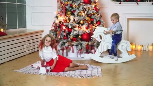 一个美丽的男孩和女孩在一棵装饰着的圣诞树的背景上挂着灯视频的预览图