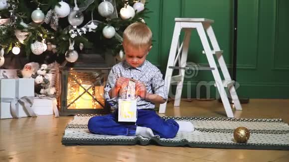 一个美丽的小男孩在一棵装饰着的圣诞树的背景上挂着灯视频的预览图